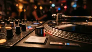 DJ-pult vinüülplaadimängijaga hämaras ööklubis, kus taustal on näha udused inimesed ja tuled.