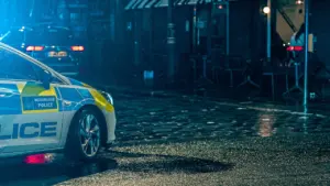 Politseiauto seismas tee ääres hämarates oludes, sümboliseerides turvalisust ja korrakaitset.