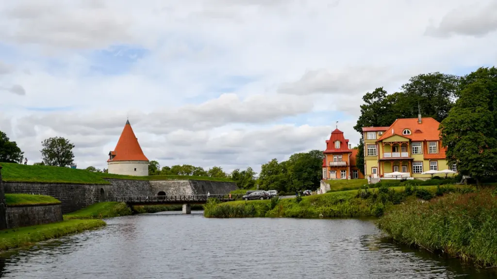 Vaade ajaloolisele Kuressaare piiskopilinnusele ja värvilistele puitvilladele rahuliku vallikraavi ääres Saaremaal.