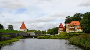 Vaade ajaloolisele Kuressaare piiskopilinnusele ja värvilistele puitvilladele rahuliku vallikraavi ääres Saaremaal.